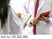 close up of senior doctor giving his younger colleagues a piece of advice concerning the diagnosis in clinic hospital. Healtcare teamwork concept. Стоковое фото, агентство Ingram Publishing / Фотобанк Лори