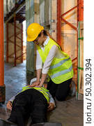 Asian worker do Cardiopulmonary Resuscitation CPR after warehouse manager lying down on warehouse floor after accident from forklift. Using for safety first and business insurance concept. Стоковое фото, агентство Ingram Publishing / Фотобанк Лори