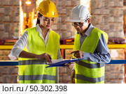 Asian warehouse manager discuss with warehouse worker using archboard to assign job with distribution warehouse in background. Reopening business warehouse technology and logistic concept. Стоковое фото, агентство Ingram Publishing / Фотобанк Лори