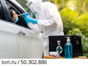COVID-19 Test kit for Drive Thru station in hospital with background of medical staff with PPE suit test to patience by throat swab. New normal healthcare drive thru service and medical concept. Стоковое фото, агентство Ingram Publishing / Фотобанк Лори