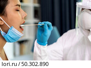 Medical staff with PPE suit test coronavirus covid-19 to asian woman by throat swab at home. New normal healthcare service at home and medical delivery concept. Стоковое фото, агентство Ingram Publishing / Фотобанк Лори