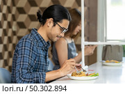 Asian customer eating out at new normal social distance restaurant with table shield partition reduce infection of coronavirus covid-19 pandemic. Restaurant new normal lifestyle. Стоковое фото, агентство Ingram Publishing / Фотобанк Лори