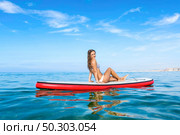 A beautiful woman sitting over a paddle surfboard and relaxing on a beautiful sunny day. Стоковое фото, агентство Ingram Publishing / Фотобанк Лори