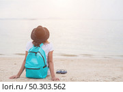Young woman with backpack sitting on lonely beach and looking into distance. Стоковое фото, агентство Ingram Publishing / Фотобанк Лори