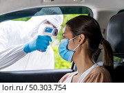 Medical staff with PPE Take Temperature for fever to asian woman before coronavirus covid-19 test at drive thru station in hospital. New normal healthcare drive thru service and medical concept. Стоковое фото, агентство Ingram Publishing / Фотобанк Лори