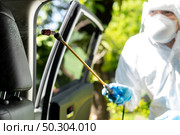 Close up of chemical alcohol spray cleaning inside car to disinfect and decontaminate coronavirus covid-19 by specialist cleaner wearing personal protective equipment PPE. New normal Hygiene concept. Стоковое фото, агентство Ingram Publishing / Фотобанк Лори