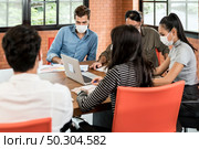 Group of asian and caucasian business person team meeting and brainstorm in meeting room after office reopen, they wear protective face mask as new normal practice to prevent coronavirus infection. Стоковое фото, агентство Ingram Publishing / Фотобанк Лори
