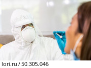 Medical staff with PPE suit test coronavirus covid-19 to asian woman by throat swab at home. New normal health care service at home and medical delivery and COVID-19 testing concept. Стоковое фото, агентство Ingram Publishing / Фотобанк Лори