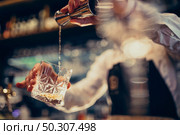 Handsome bartender making drinking and cocktails at a counter. Стоковое фото, агентство Ingram Publishing / Фотобанк Лори