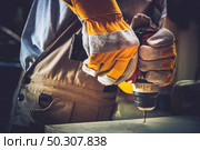 Little of Residential Construction Works. Men Fixing Wooden Shelf with His Driller. Стоковое фото, агентство Ingram Publishing / Фотобанк Лори