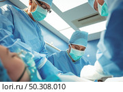 Team of surgeons performing operation in operation theater at hospital. Стоковое фото, агентство Ingram Publishing / Фотобанк Лори