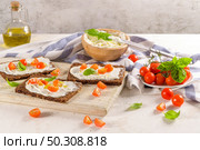 Rye bread bruschetta with cream cheese, olive oil and basil dip, cherry tomatoes, fresh basil leaves on wooden board. Стоковое фото, агентство Ingram Publishing / Фотобанк Лори
