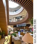 The interior of a luxury multi-storey shopping mall with an escalator and a coffee shop on the ground floor. Russia. Moscow. 22.06.25. Редакционное фото, фотограф Ярославский Максим / Фотобанк Лори
