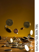 The silver and golden coins and falling coins on wooden table background. The silver and golden coins and falling coins on wooden background. Стоковое фото, агентство Ingram Publishing / Фотобанк Лори
