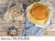 Portuguese sponge cake wrapped in the typical paper used on the baking, on wooden background with painted easter eggs decoration. Стоковое фото, агентство Ingram Publishing / Фотобанк Лори