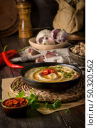 Delicious hummus in ceramic bowl. Colorful snack composition on a black wooden background. Стоковое фото, агентство Ingram Publishing / Фотобанк Лори