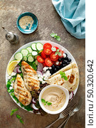 Chicken breast grilled with fresh vegetables, olives, feta cheese, flatbread and hummus, top view. Стоковое фото, агентство Ingram Publishing / Фотобанк Лори