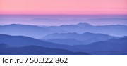 Mountain ridges in fog and pink sky at sunset in autumn. Beautiful landscape with foggy mountain valley, hills, forest at dusk in blue hour in fall. Aerial view of hills. Top view. Nature background. Стоковое фото, агентство Ingram Publishing / Фотобанк Лори