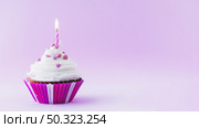 birthday cupcake with illuminated candle purple background. Стоковое фото, агентство Ingram Publishing / Фотобанк Лори