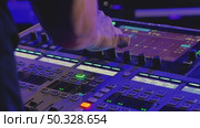 A close-up of a DJ's hand adjusting the controls on a music mixing console. Bright blue and green lights emphasize the dynamic atmosphere of a live performance. Стоковое видео, видеограф Воловодов Владимир / Фотобанк Лори