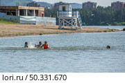 Дети весело проводят время, купаясь на пляже городского озера, город Железногорск Красноярский Край. Редакционное фото, фотограф Анатолий Володин / Фотобанк Лори
