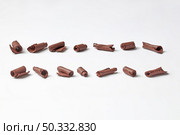 Even lines of arranged shavings of organic dark chocolate in rows on white background. Row of raw chocolate shavings. Стоковое фото, агентство Ingram Publishing / Фотобанк Лори