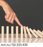 domino game made with wooden pieces representing finances struggles. Стоковое фото, агентство Ingram Publishing / Фотобанк Лори