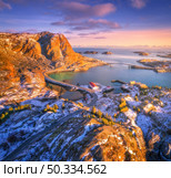 Aerial view of beautiful mountains, bridge, small islands in the sea, road, purple sky at sunset. Lofoten islands, Norway in winter. Top view of road, snowy rocks, stones, sea coast, water. Top view. Стоковое фото, агентство Ingram Publishing / Фотобанк Лори