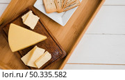 triangular cheese wedges wooden tray against white desk. Стоковое фото, агентство Ingram Publishing / Фотобанк Лори