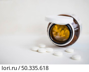 white round pills spilling from brown bottle white background. Стоковое фото, агентство Ingram Publishing / Фотобанк Лори