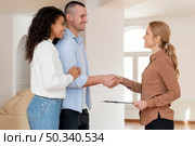 side view female realtor shaking hands with couple new house deal. Стоковое фото, агентство Ingram Publishing / Фотобанк Лори