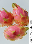Three vibrant pink dragon fruits with green tips submerged in clear water, photographed close-up with bright lighting, highlighting texture and freshness. Стоковое AI-изображение, AI-художник Катерина Бондарец / Фотобанк Лори