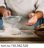 baker sifting wheat flour through steel sieve knead dough. Стоковое фото, агентство Ingram Publishing / Фотобанк Лори
