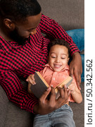 black father cute son reading book couch. Стоковое фото, агентство Ingram Publishing / Фотобанк Лори