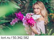 blonde young woman standing garden holding orchid. Стоковое фото, агентство Ingram Publishing / Фотобанк Лори