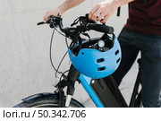 close up bicyclist putting helmet bycicle handle. Стоковое фото, агентство Ingram Publishing / Фотобанк Лори