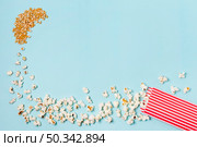 corn seeds turns into popcorns enter popcorn box against blue backdrop. Стоковое фото, агентство Ingram Publishing / Фотобанк Лори