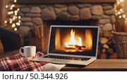 Laptop with a white screen mock up, indoor near burning fireplace in rustic style, with cozy blanket and cup of coffee. Seasonal remote work, internet, shopping. AI generated. Стоковое AI-видео, аниматор Ольга Симонова / Фотобанк Лори
