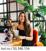 smiling beautiful young woman with cocktail smartphone digital tablet restaurant. Стоковое фото, агентство Ingram Publishing / Фотобанк Лори