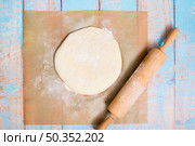 wooden rolling pin flat dough parchment paper wooden table. Стоковое фото, агентство Ingram Publishing / Фотобанк Лори