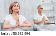healthy old couple sitting lotus pose with praying hands. Стоковое фото, агентство Ingram Publishing / Фотобанк Лори