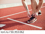 low section male athlete start line tying his shoelace running track. Стоковое фото, агентство Ingram Publishing / Фотобанк Лори