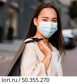 woman with medical mask out sale shopping spree with shopping bag. Стоковое фото, агентство Ingram Publishing / Фотобанк Лори
