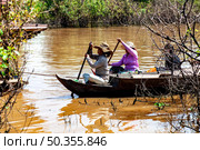Life on Water at Tonle Sap Lake Shows Cambodian Women Traveling on a Boat (2014 год). Редакционное фото, фотограф Aleksandr Golubev / Фотобанк Лори
