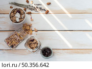 jar spilled granola near cornflakes dry fruits chocolate chips wooden plank. Стоковое фото, агентство Ingram Publishing / Фотобанк Лори