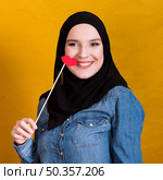 smiling muslim woman holding paper prop shape red lips backdrop. Стоковое фото, агентство Ingram Publishing / Фотобанк Лори