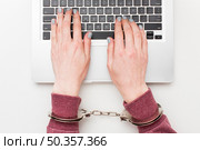 top view hands with handcuffs working laptop. Стоковое фото, агентство Ingram Publishing / Фотобанк Лори