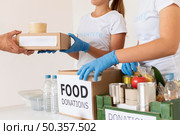 volunteers with gloves handing boxes with food donation. Стоковое фото, агентство Ingram Publishing / Фотобанк Лори