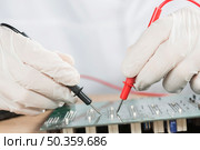 close up technician hand examining computer circuit board with digital multimeter. Стоковое фото, агентство Ingram Publishing / Фотобанк Лори