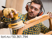 carpenter softening edges wooden furniture with electric sander. Стоковое фото, агентство Ingram Publishing / Фотобанк Лори